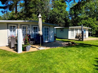 Fotografi av en ferdigstilt campinghytte eller mobilhus med en terrasse og omgivelser.