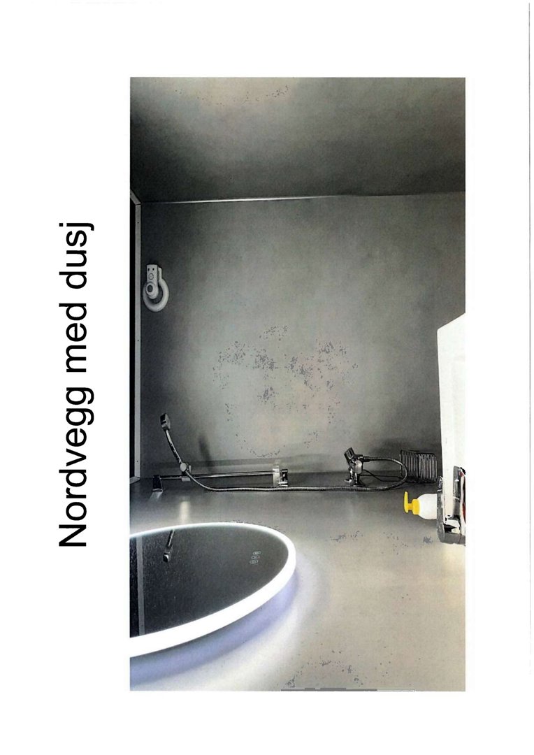 Fotografi av en nordvegg med dusj, inkludert dusjhode, slange, veggventil og del av en rund speil eller badekar.