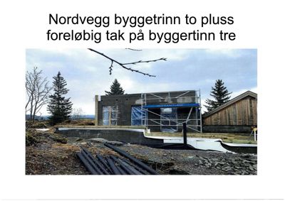 Fotografi av en bygning under oppføring (scaffolding, takarbeider) med tekstbeskrivelse 'Nordvegg byggetrinn to plass foreløbig tak på byggetinn tre'.