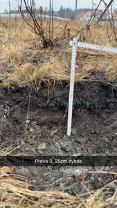 Fotografi av et jordprøvetaking med målestokk og tekst 'Prøve 3. 25cm dybde'.