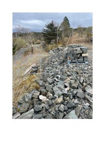 Fotografi som viser en haug med steinblokker og grus, sannsynligvis på et byggeplass eller ved en vei.