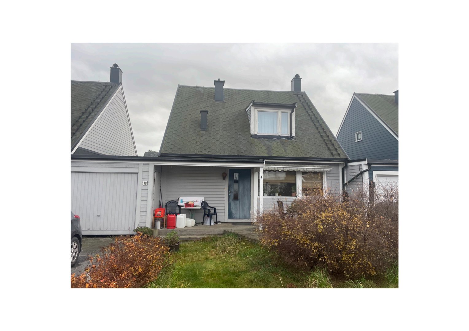 Fotografi av en eksisterende enebolig med garasje, fortau og hage.