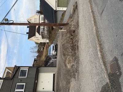 Fotografi av en eksisterende eller planlagt bygning sett fra gaten, med bil og nabolag i bakgrunnen.