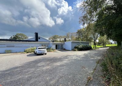 Fotografi av en hvit enebolig sett fra fortaket med en bil parkert foran.