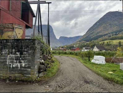 Fotografi av en vei i et landsbyområde med fjell i bakgrunnen, sett fra et lavt nivå.