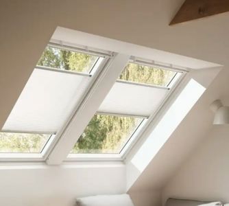 Fotografi av et takvindu med persienner i et skrått takrom.