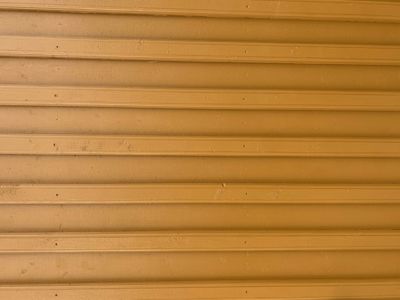 Fotografi av en gul, horisontalt ribbet fasade, sannsynligvis av tre eller kompositt.