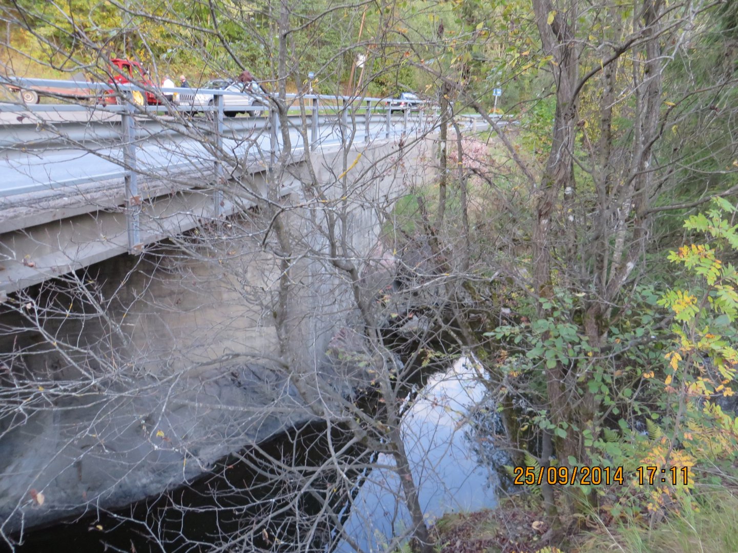 Fotografi av en bro over en elv eller bekke, sett fra bakken.