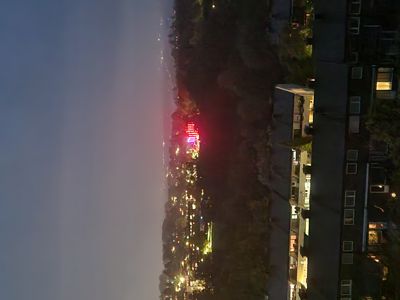 Et fotografi av en bygning og et nabolag tatt om kvelden, med lys fra vinduer og i bakgrunnen.