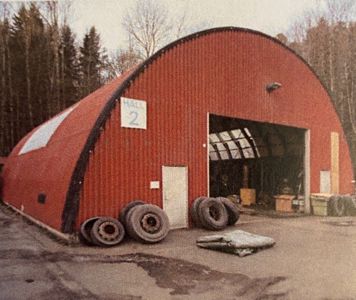 Fotografi av en rød, halvsirkelformet bygning med skiltet 'HALL 2' og flere dører.