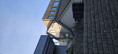 Fotografi av en bygning sett fra bakken mot himmelen, som viser fasadeelementer, tak og vinduer.