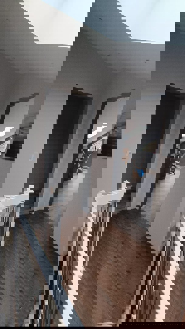 Fotografi av en innendørs trapp og gang i en bolig, med utsikt mot et rom med treningsutstyr.