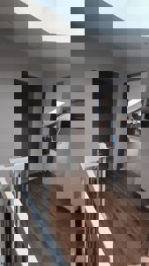 Fotografi av en innendørs trapp og gang i en bolig, med utsikt mot et rom med treningsutstyr.