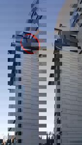 Fotografi av en bygning sett fra nede, som viser fasaden med hvite paneler, takrenne og et vindusfelt i øvre del.