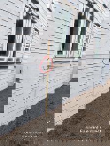 Fotografi av fasade mot vest på en bygning under oppføring eller etter ferdigstillelse, med målstokk og tekstbeskrivelse.