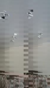 Fotografi av et tak med en innbygd spotlys og en hvit røykvarsel (røykdetektor). Bildet viser også en del av veggen nederst.