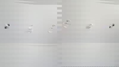 Fotografi av en hvit takflate med to innbygde spotlys og en røykvarsler i midten.