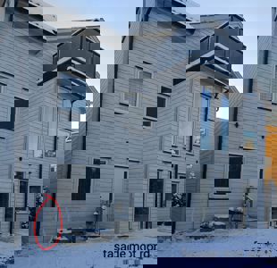 Fotografi av en hvitmalt trehusfasade med snø, vinduer og en balkong. Bildet har teksten 'fasade mot nord' i bunnen.