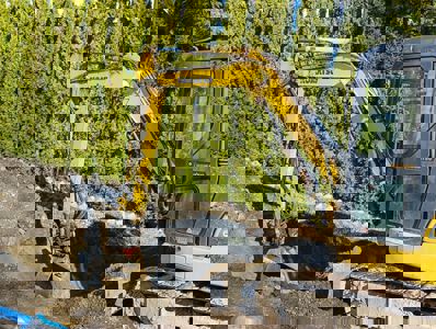 Fotografi av en gulegget gravemaskin (Komatsu) som jobber med å grave ut jorden på en byggeplass.