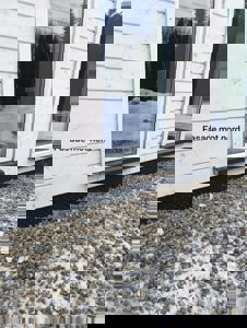 Fotografi av en fasade med hvite panelvegger, store vinduer, grusdekke og snø. Bildet har teksten 'Fasade mot nord' på seg.