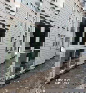 Fotografi av en ferdig eller nesten ferdig bygning sett fra utsiden, med tekst 'Fasade mot vest' nederst.