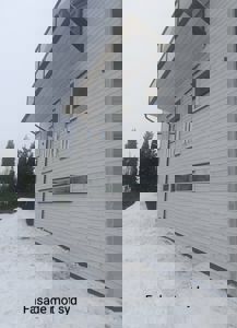 Fotografi av en hvit fasade på en bygning med snø på bakken og et tekstfelt som sier 'Fasade mot syd'.