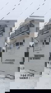 Fotografi av en hvitbeiset fasade på et hus med et moderne balkong, sett fra nede. Bildet har teksten 'Fasade mot syd' nederst.