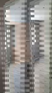 Fotografi av et tomt rom sett gjennom en døråpning. Rommet har lyse gulv, beige vegger, hvite lister, innbygde lysarmaturer i taket og et vindu på den ene veggen.