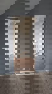 Fotografi av et interiør med gråmalingde vegger, lyse gulv og en døråpning som viser inn i et annet rom.