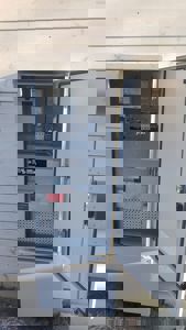 Fotografi av en åpen elektrisk skuff (fordelingsboks) montert på en hvit, panelert fasade.