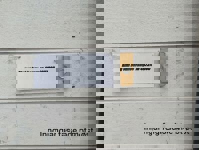 Fotografi av en inngangsdør med et skilt som sier 'Ring ved behov rampe 46237000' og en gullfarget dørtelefon. Bildet har også teksten 'Inngang fasade mot øst' i bunnen.