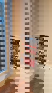 Fotografi av en innbygd vannfordeler (manifold) med rødt og hvitt rørverk i en vegg, sett fra et rom.