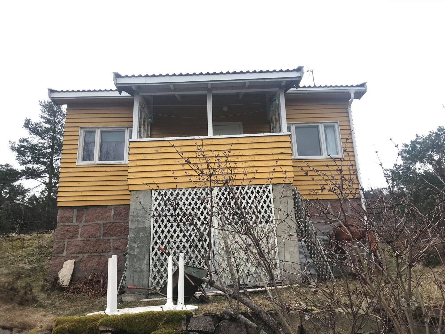 Fotografi av en gul fasettvegg med steinfundament, sett fra foran.