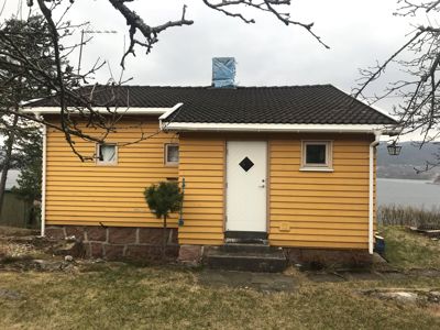 Fotografi av en gul ferdigbygd enebolig sett fra fronten.