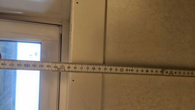 Fotografi av en vegg og dørkarm med en målebånd som viser en måling.