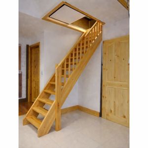 Fotografi av en innvendig trapp i tre som fører opp til et loft eller etasje med et takvindu.