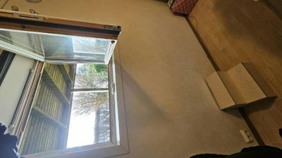 Fotografi av et roms innvendige vegg, gulv og et vindu som er åpnet mot utsiden.