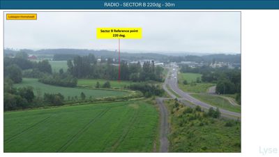 Fotografi av et landskap med en vei og en markert referansepunkt for en radiosender.