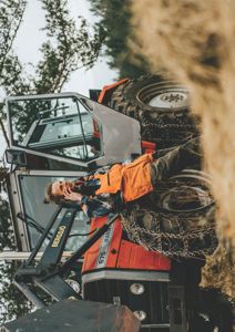 Fotografi av en mann som ligger på en traktor i et landbruksmiljø.