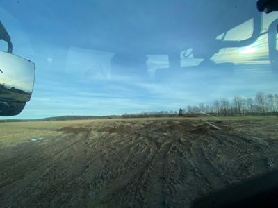 Fotografi tatt fra innendørs (kanskje kjøretøy eller bygning) som viser utsikt over en skog og himmel.