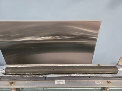 Fotografi av en metallplate og en rulle isolasjon som ligger på en arbeidsbenk.