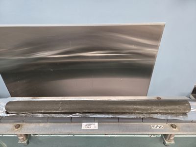 Fotografi av en metallplate og en rulle isolasjon som ligger på en arbeidsbenk.