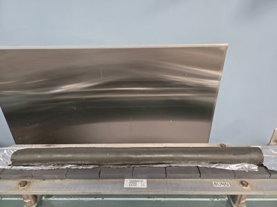 Fotografi av en metallplate og en rulle isolasjon som ligger på en arbeidsbenk.