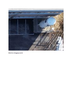 Luftfoto av en bygning med et tankanlegg og parkeringsplass, tatt før en ombygging.