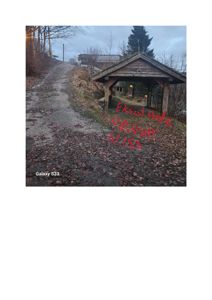 Fotografi av en eksisterende bygning (en hytte eller uthus) sett fra en vei, med håndskrevet tekst overlagt.