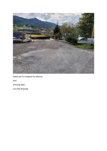 Fotografi av et dekke sett fra innkjørsel fra fylkesveien, med utsikt over vann og fjell.