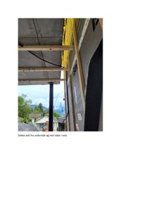 Fotografi av en byggeplass som viser underside av et betongdekke, en vegg med isolasjon og en svart stålstøtte. Bildet viser også nabolaget i bakgrunnen.