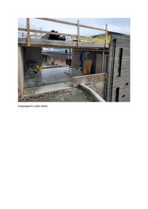 Fotografi av et bygg under oppføring, som viser inngangsparti under et dekke.