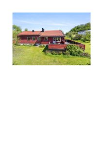 Fotografi av en rød trehus med takterreng og tilhørende terrasse, sett fra bakgårdssiden.