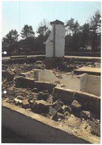 Fotografi av en bygning under riving eller ombygging, som viser fundamentet og en stående skorstein.